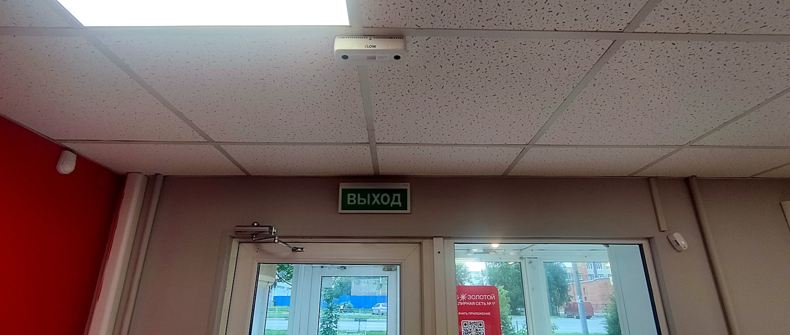 Камера видеонаблюдения над входом в помещение с табличкой Выход